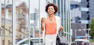 young smiling african american businesswoman with coffee cup in city