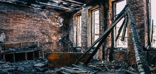 Burnt room interior with walls, furniture and floor in ash and coal, ruined building after fire, toned