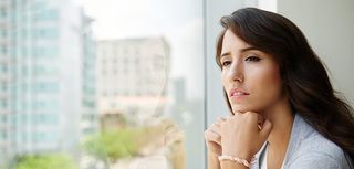 Pensive young woman looking through the window