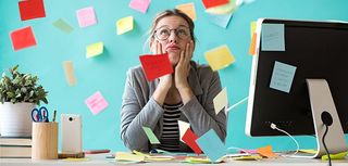 Shot of stressed young business woman looking up surrounded by post-its in the office.