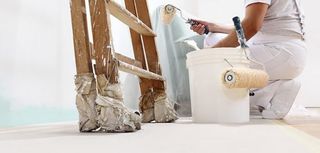 painter at work with a roller, bucket and scale, from below view