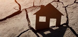 Paper house on cracked earth, crisis concept