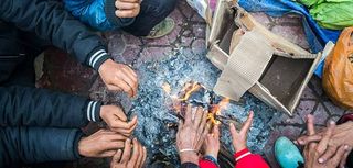 Hands of rural minority people warming up around the fire during the cold weather days in mountaious region in Vietnam